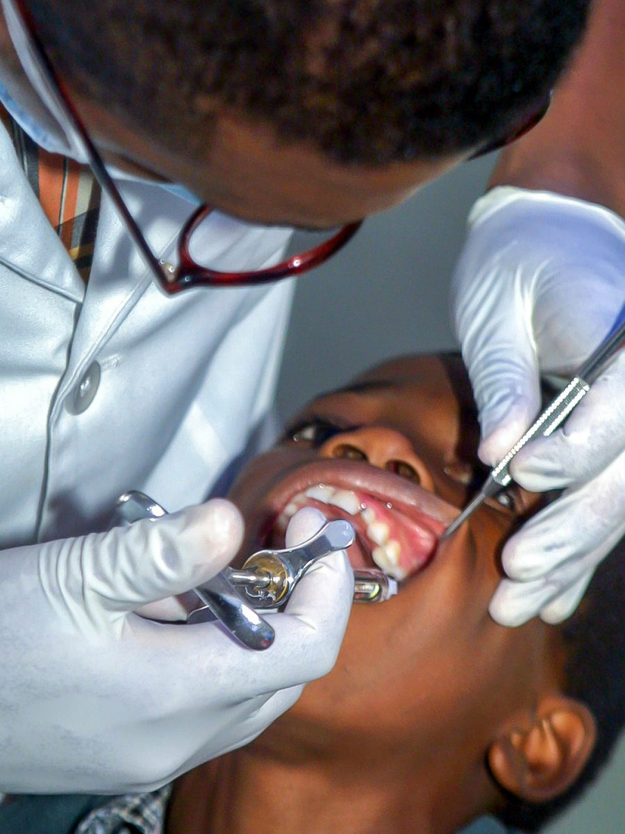 A Glaze dentist examining a young patient with careful, gloved hands